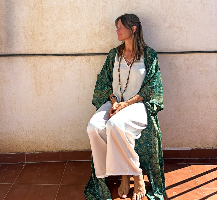 Malin Rydesjö sitting in the sunshine beside a pale wall
